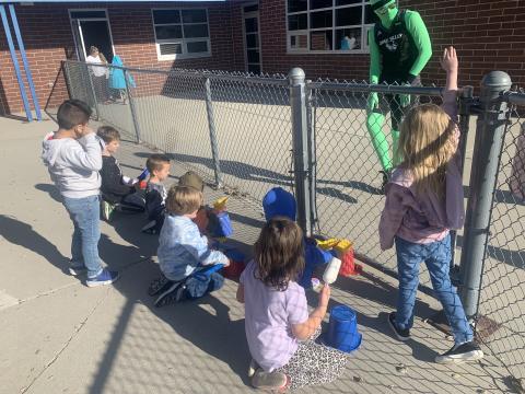 Students from Kindergarten showing a Green Man their drumming skills