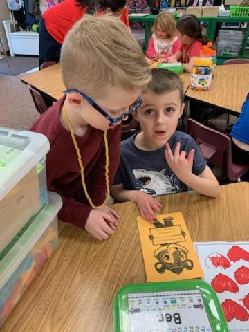 2nd grader teaching a kindergarten student how to say "Happy New Year"